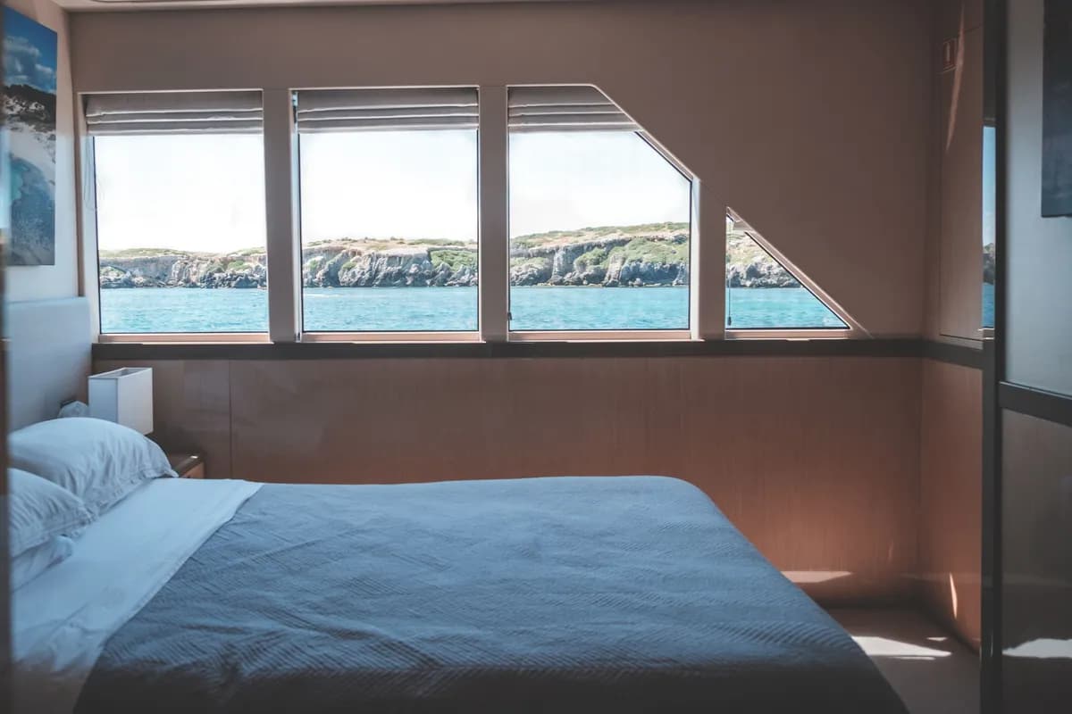Exemple d'image BookNoFees : cabine de bateau lumineuse avec un lit et de grandes fenêtres donnant sur la mer
