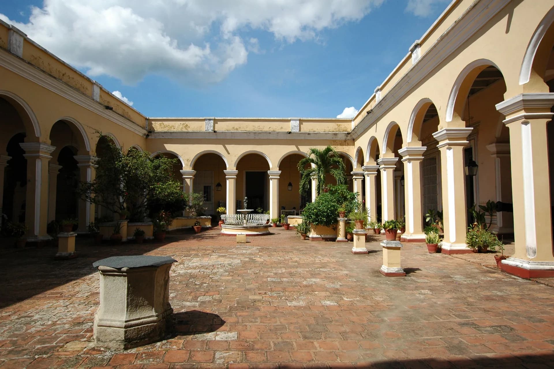 Exemple d'image BookNoFees : cour intérieure cubaine avec des arcades jaunes et des plantes