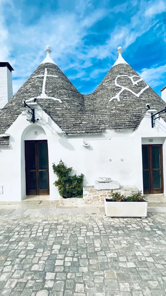 BookNoFees Beispielbild: Weiße Trulli mit steinernen Kegeldächern und kleinen Eingangstüren