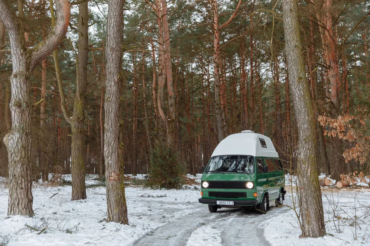 Exemple d'image BookNoFees : un camping-car vert à toit surélevé dans une forêt enneigée