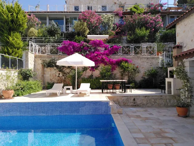 BookNoFees: Ferienwohnung in Kalkan, Kas, Antalya, Antalya, Türkei – Poolterrasse mit Liegestühlen, Sonnenschirm und blühenden Bougainvillea an Steinmauern