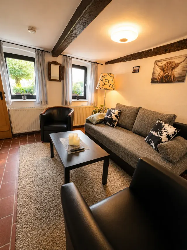 BookNoFees: Ferienwohnung in Halenbach, Rheinland-Pfalz, Deutschland – Wohnzimmer mit Sofa, Sesseln, Couchtisch und sichtbaren Holzbalken an der Decke