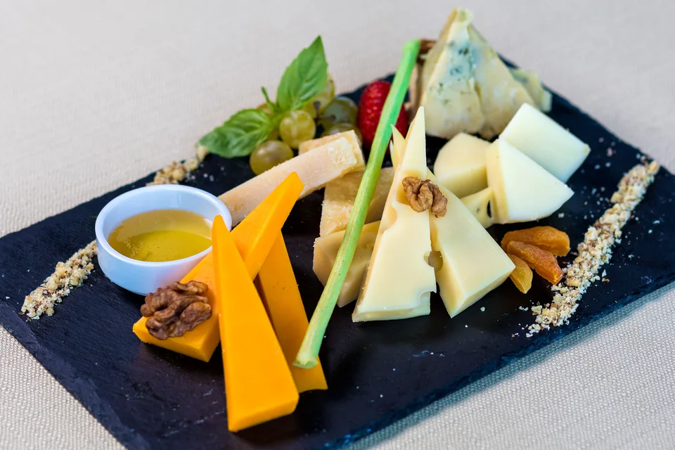 BookNoFees: Photo d’illustration : Assortiment de fromages accompagnés de fruits et de noix sur un plateau de dégustation