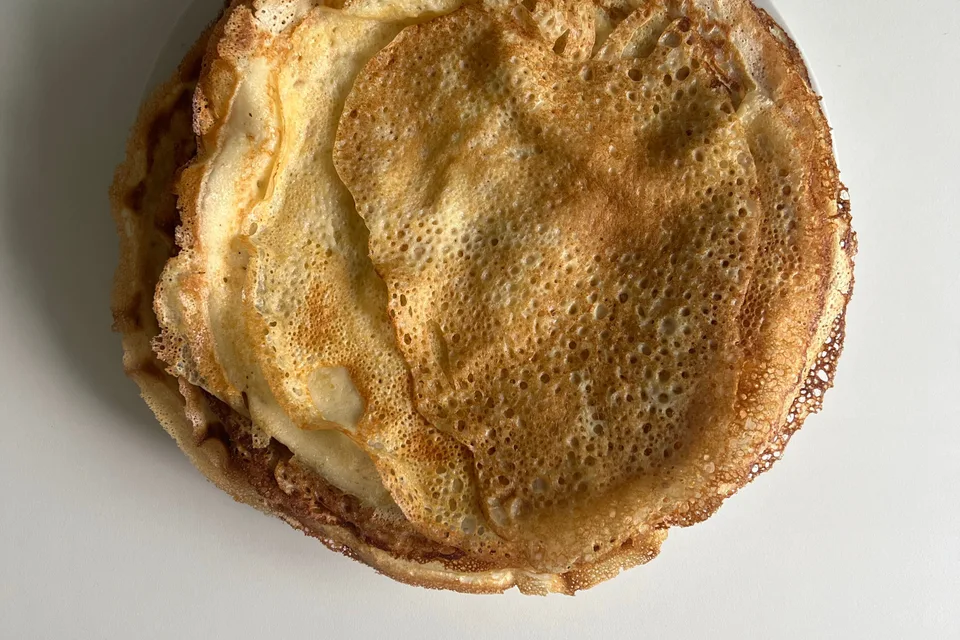 BookNoFees: Photo d’illustration : De fines crêpes dorées sur une assiette blanche