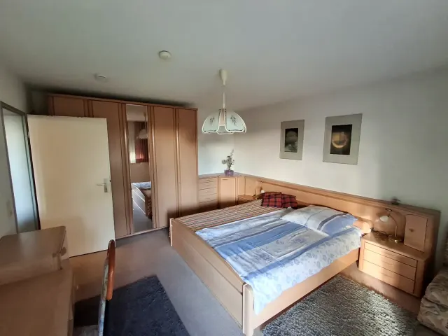 BookNoFees : location de vacances à Gailingen, Bade-Wurtemberg, Allemagne – Chambre avec un lit double, une armoire en bois avec miroir et des tables de chevet