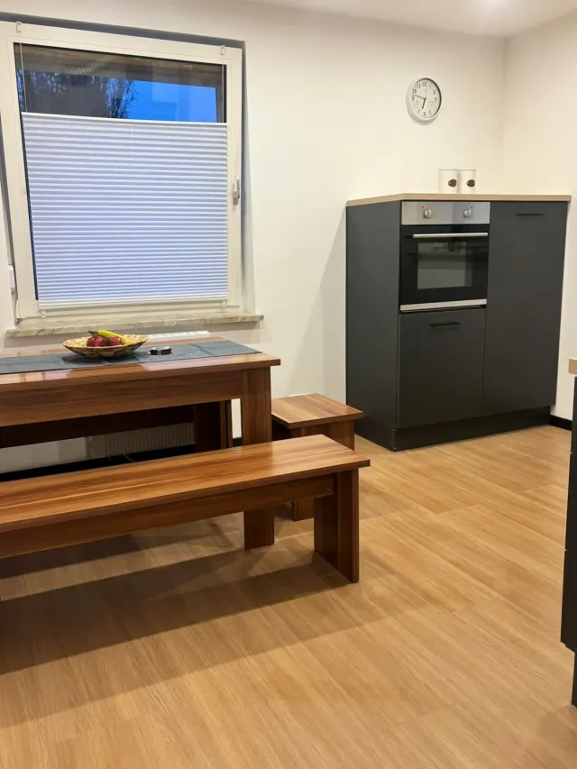 BookNoFees : location de vacances à Bodenwerder – Cuisine avec table à manger en bois, banc, four encastré et fenêtre équipée d'un store