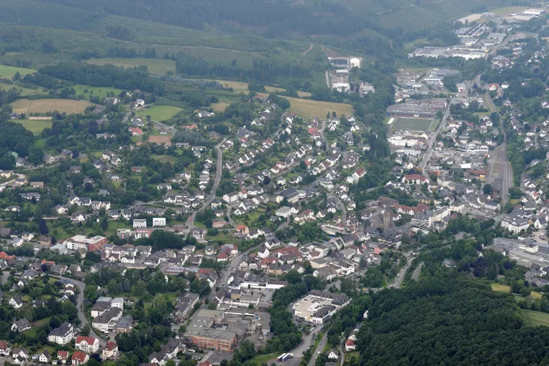 La ville de Sundern vue du ciel, avec ses maisons qui s'étendent le long de la vallée de la Röhr, entre des collines boisées