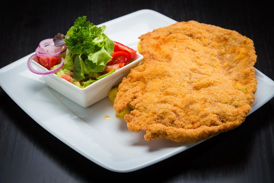 BookNoFees: Beispielfoto: Paniertes Schnitzel mit Beilagensalat auf einem weißen Teller