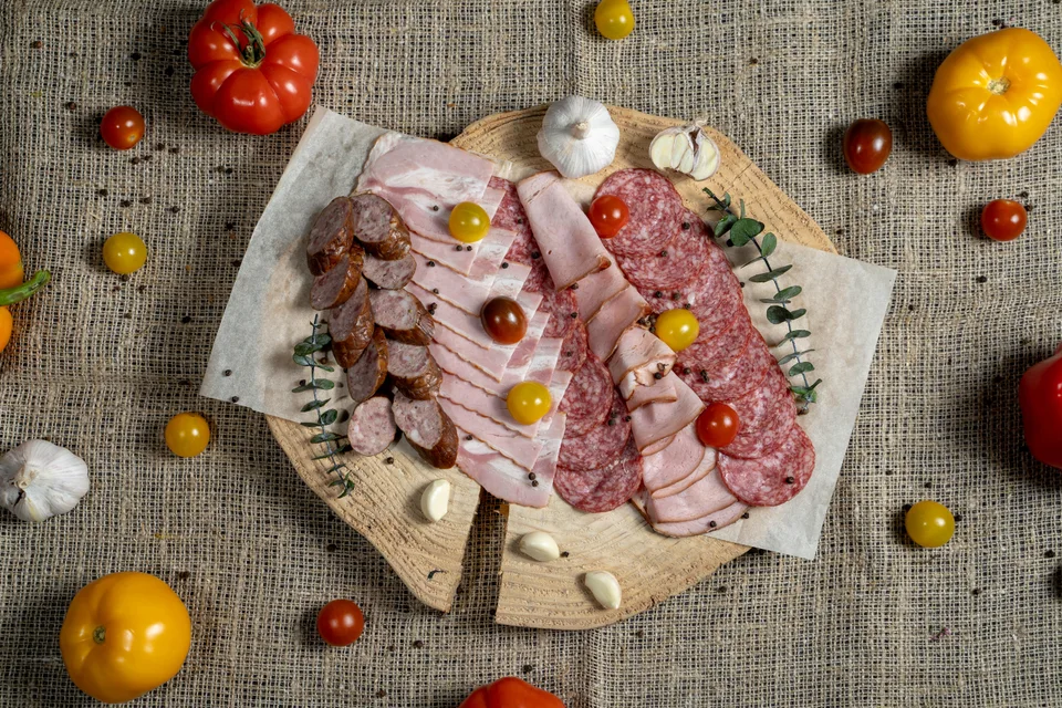 Photo d’illustration : Tranches de charcuterie et de saucisses sur une planche en bois